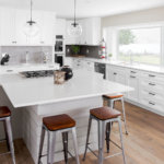 White shaker cabinets, gray island, quartz and wood floors in a renovated lakefront kitchen.