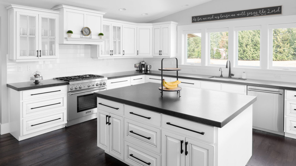 Custom white modern farmhouse kitchen with stainless steel appliances, wood flooring and black granite countertops.
